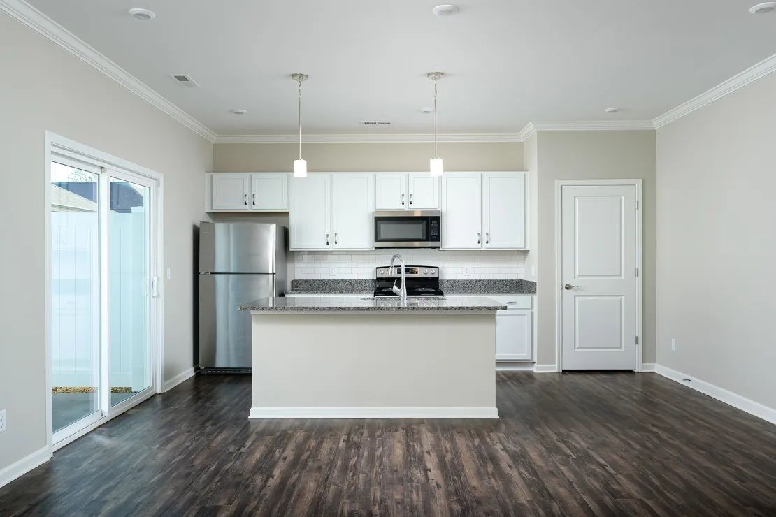 An empty kitchen with white cabinets and stainless steel appliances.
