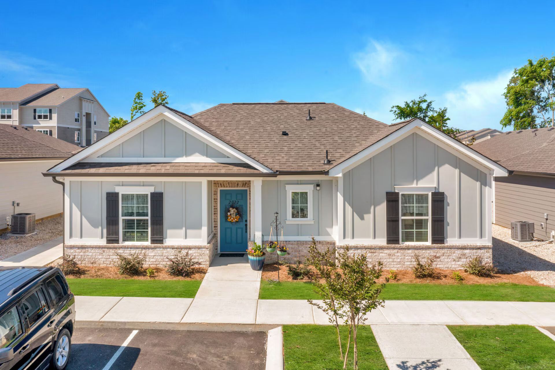 A car is parked in front of a house with a blue door.