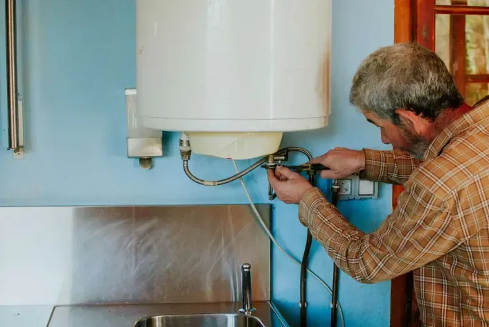 A man is finishing the installation of a water heater.