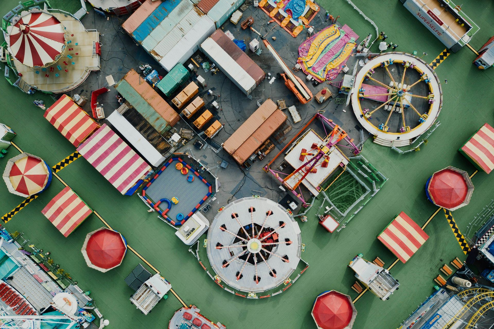 An aerial view of a carnival with ferris wheels and tents.