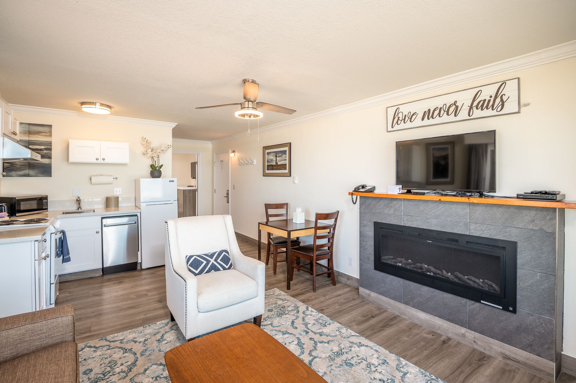 White kitchen with cabinets, appliances, artwork, and a small countertop.