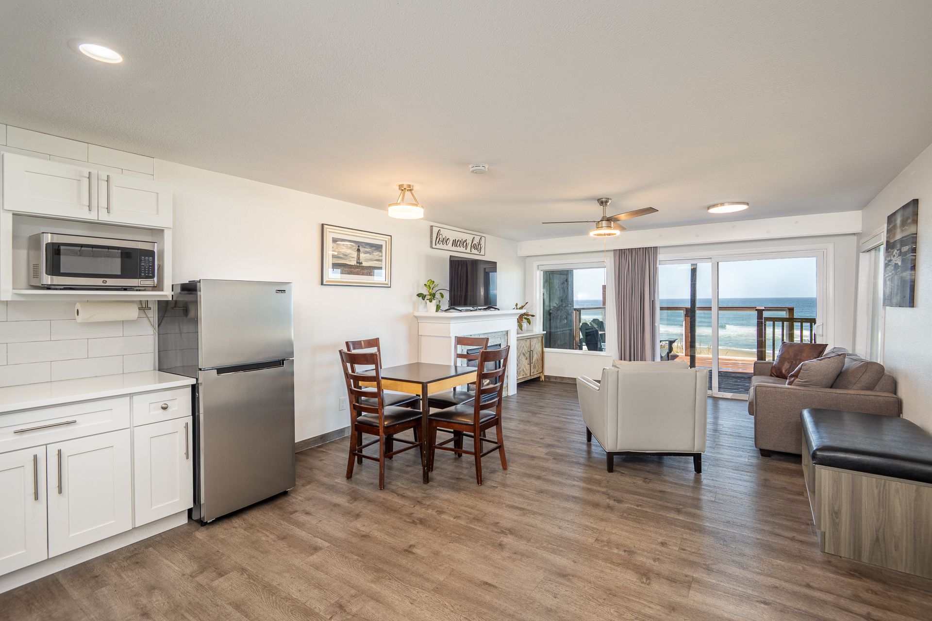 Bedroom with king-sized bed, white linens, beach view balcony, art, neutral walls, natural light.