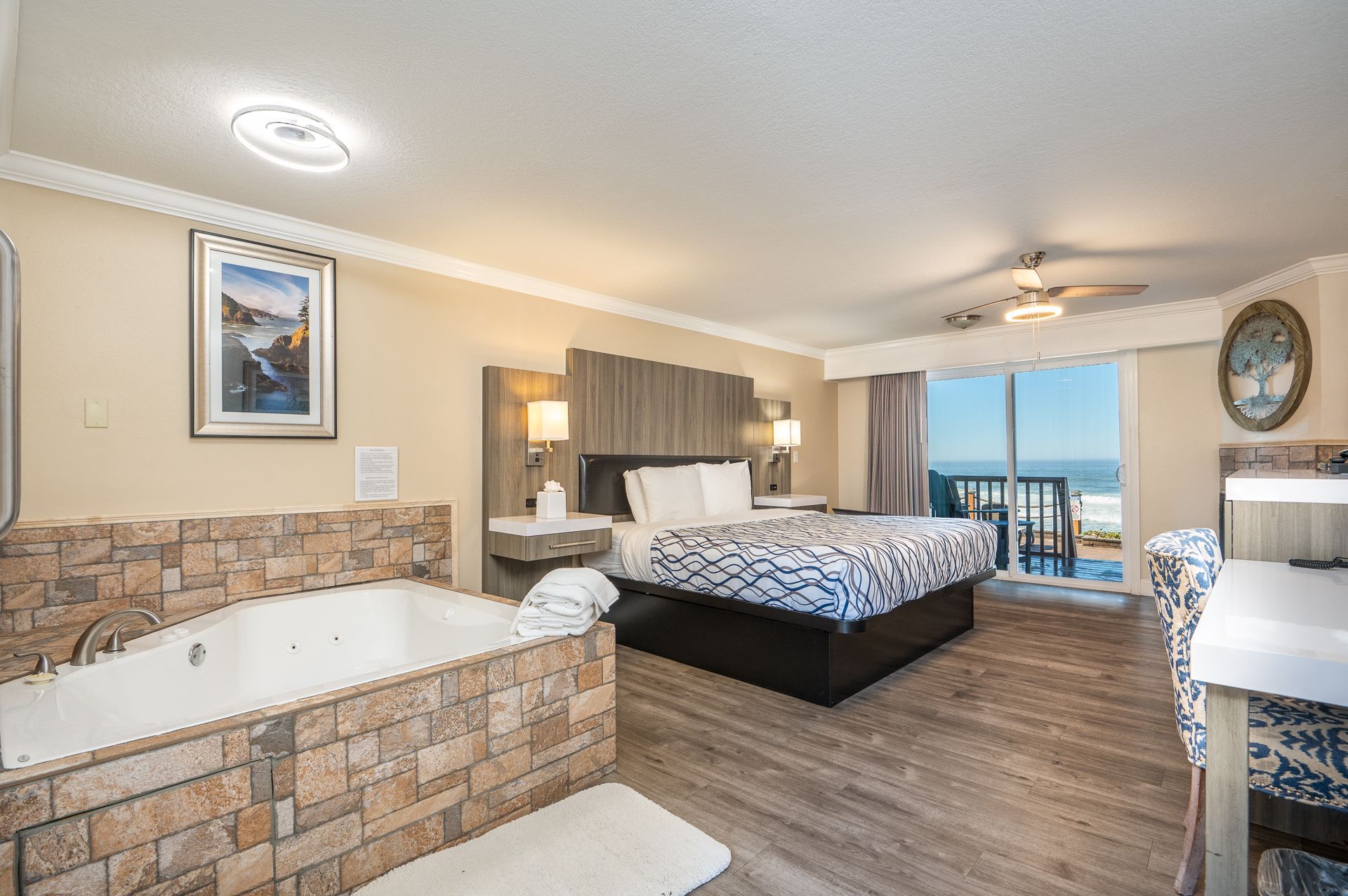 Hotel room with a king-sized bed, jacuzzi tub, and ocean view from a balcony.