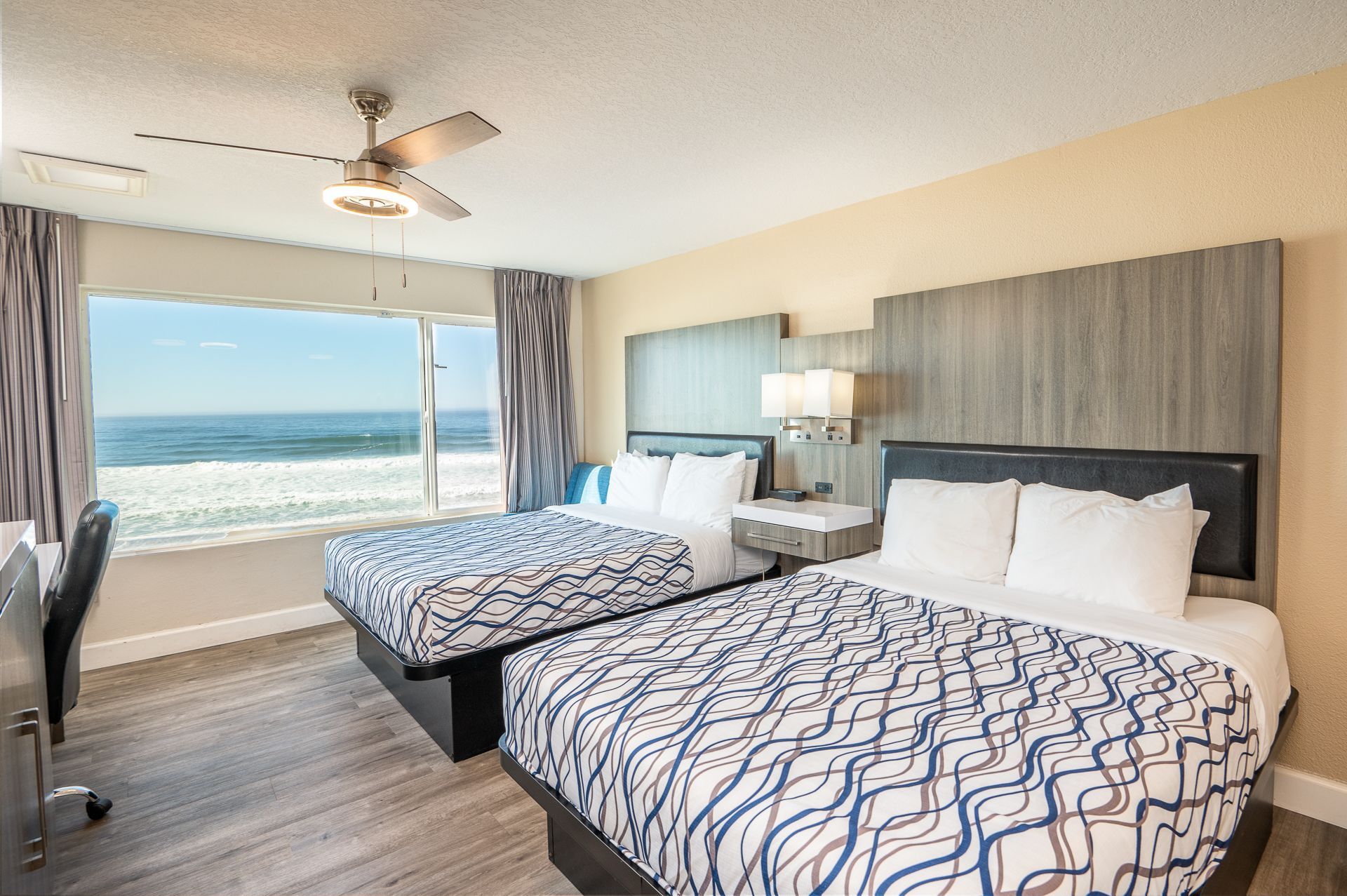 Beachfront hotel room with two beds, ocean view, and neutral decor.