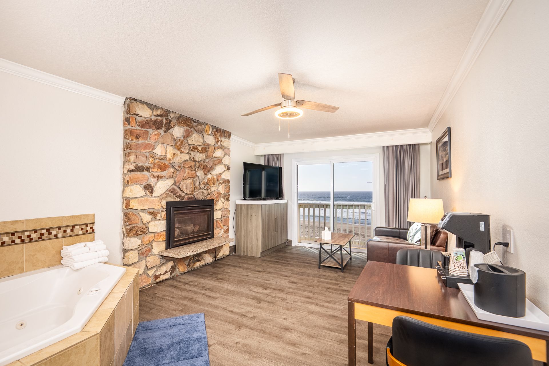 Room with a jacuzzi, fireplace, ocean view, sofa, and small coffee table.