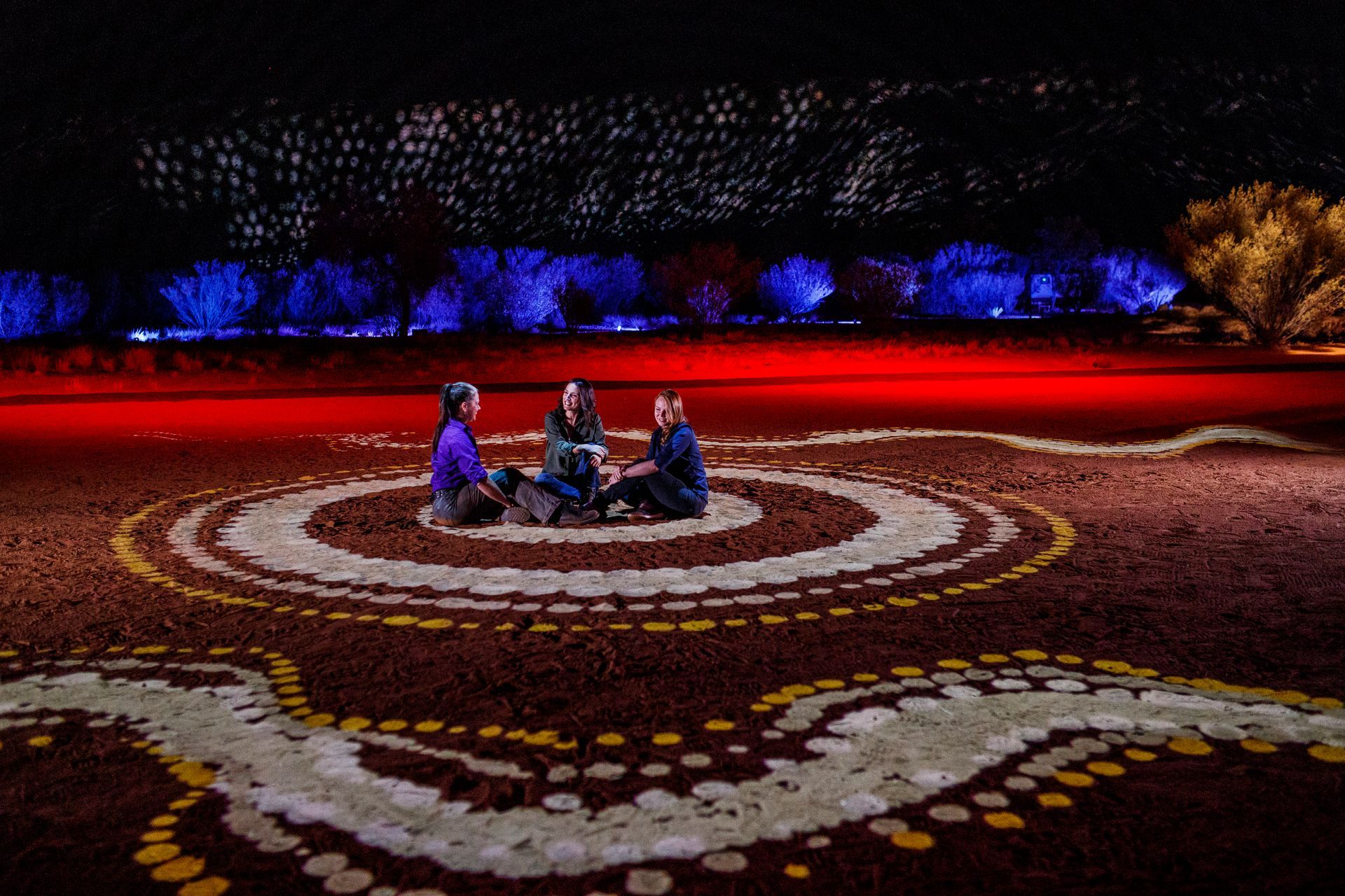 a group of people are sitting in a circle on the ground .