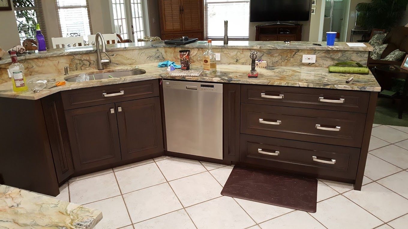 A kitchen with stainless steel appliances , granite counter tops , and brown cabinets.
