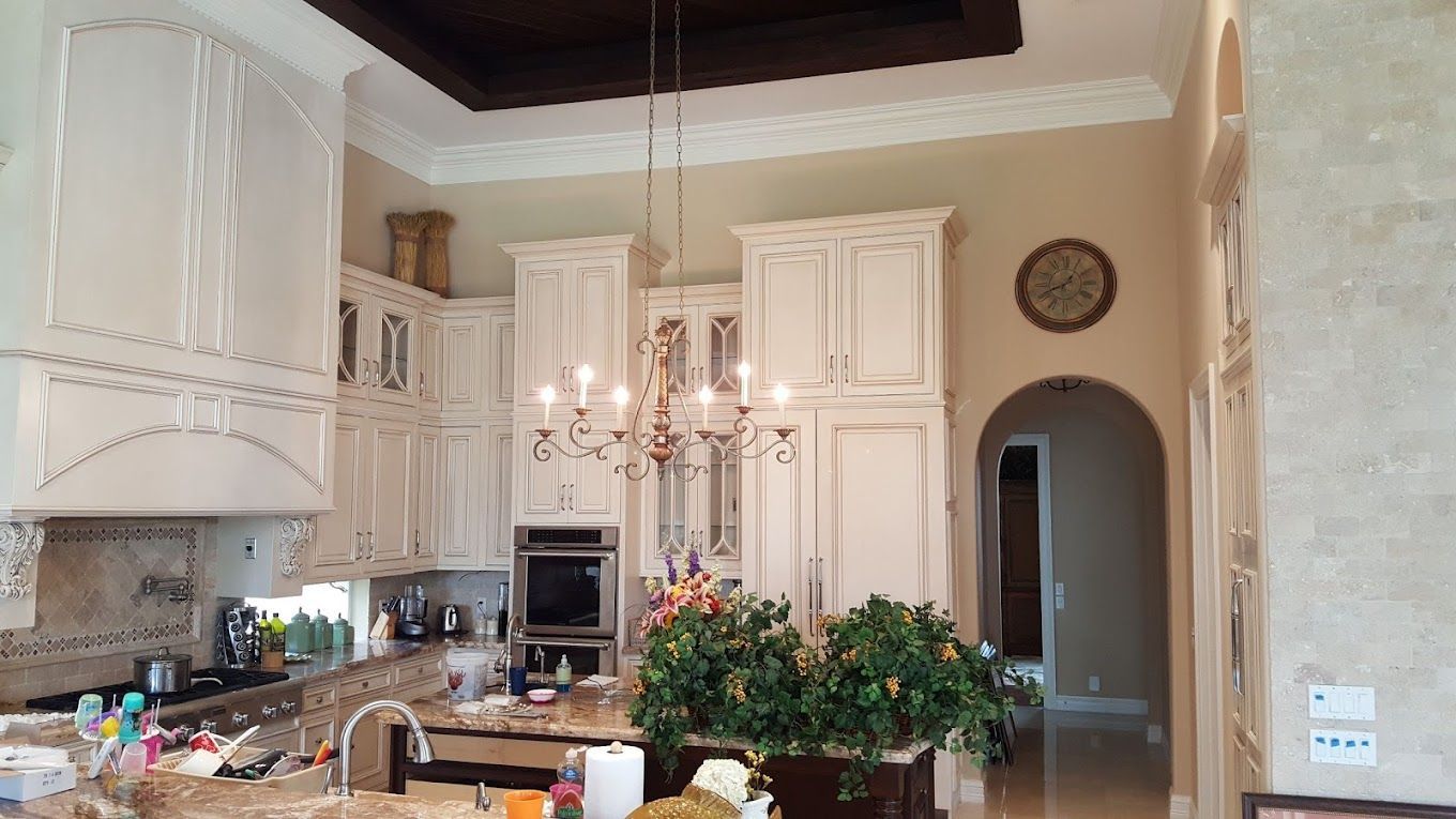 A kitchen with white cabinets and a chandelier hanging from the ceiling.