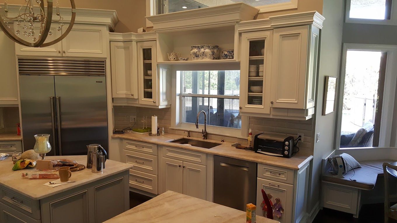 A kitchen with white cabinets , stainless steel appliances and a large island.