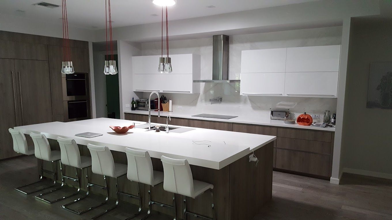 A kitchen with a large island and white chairs