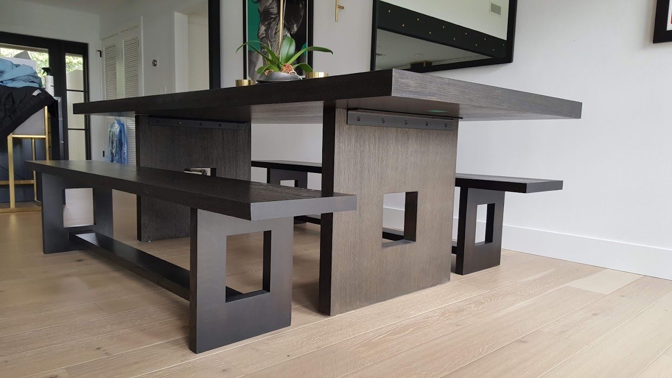 A dining room table with two benches and a mirror on the wall.