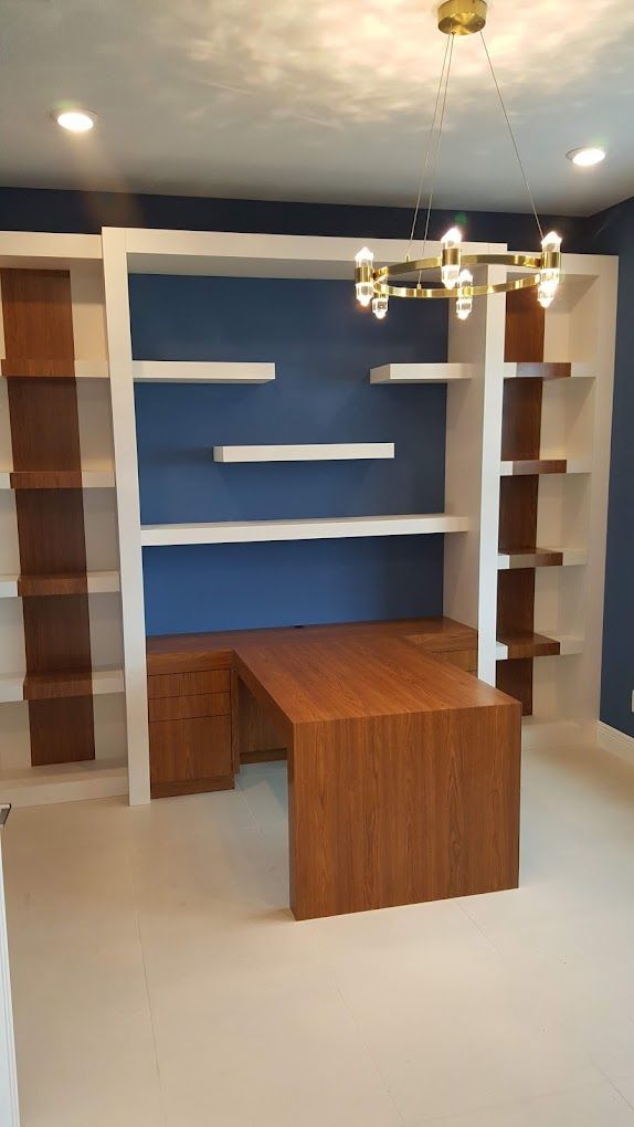 A room with a desk , shelves , and a chandelier.