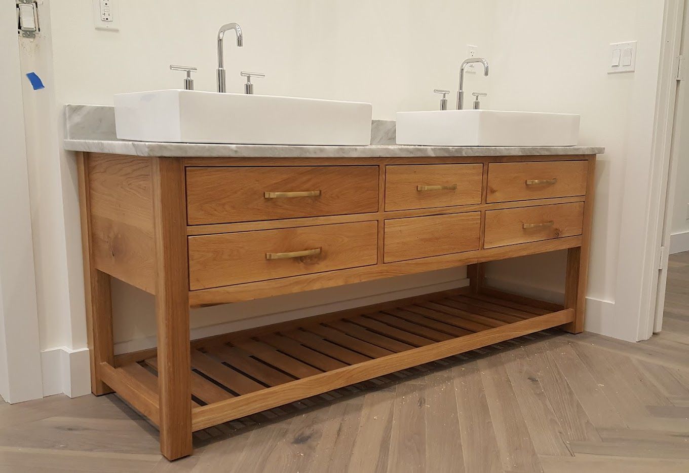 A bathroom vanity with two sinks and a shelf underneath it.