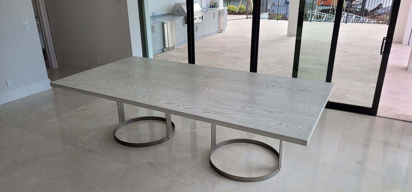 A white dining table is sitting in a room next to a sliding glass door.