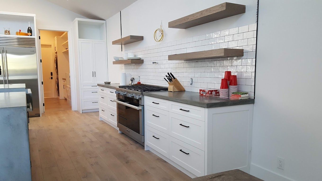 A kitchen with white cabinets , stainless steel appliances , a stove and a refrigerator.