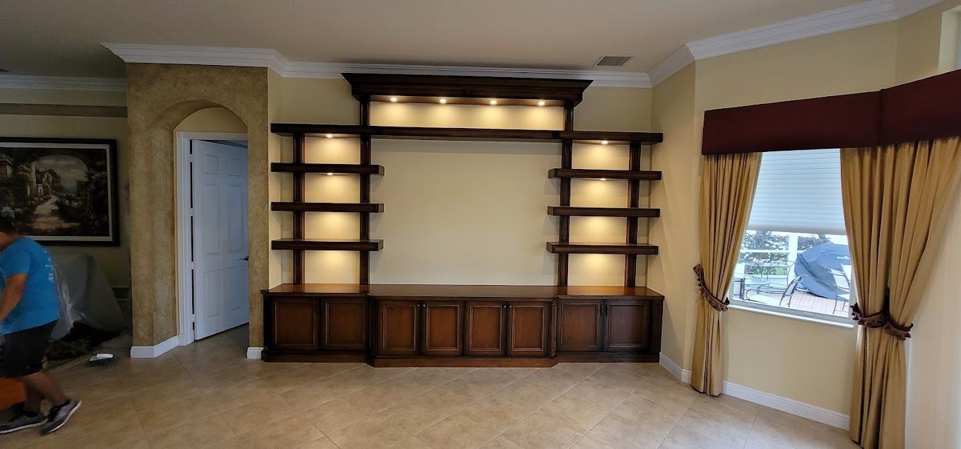 A man is standing in a living room with a large entertainment center.