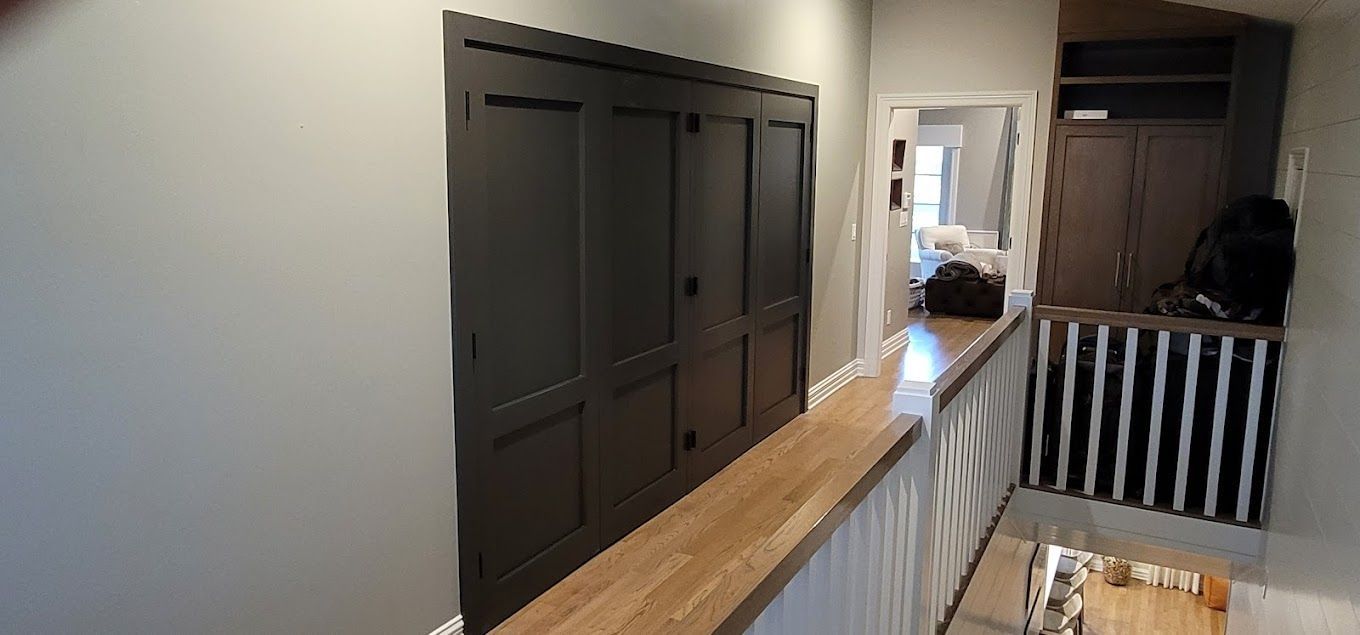 A hallway with black doors and a wooden floor
