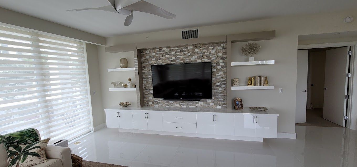 A living room with a flat screen tv on the wall and a ceiling fan.