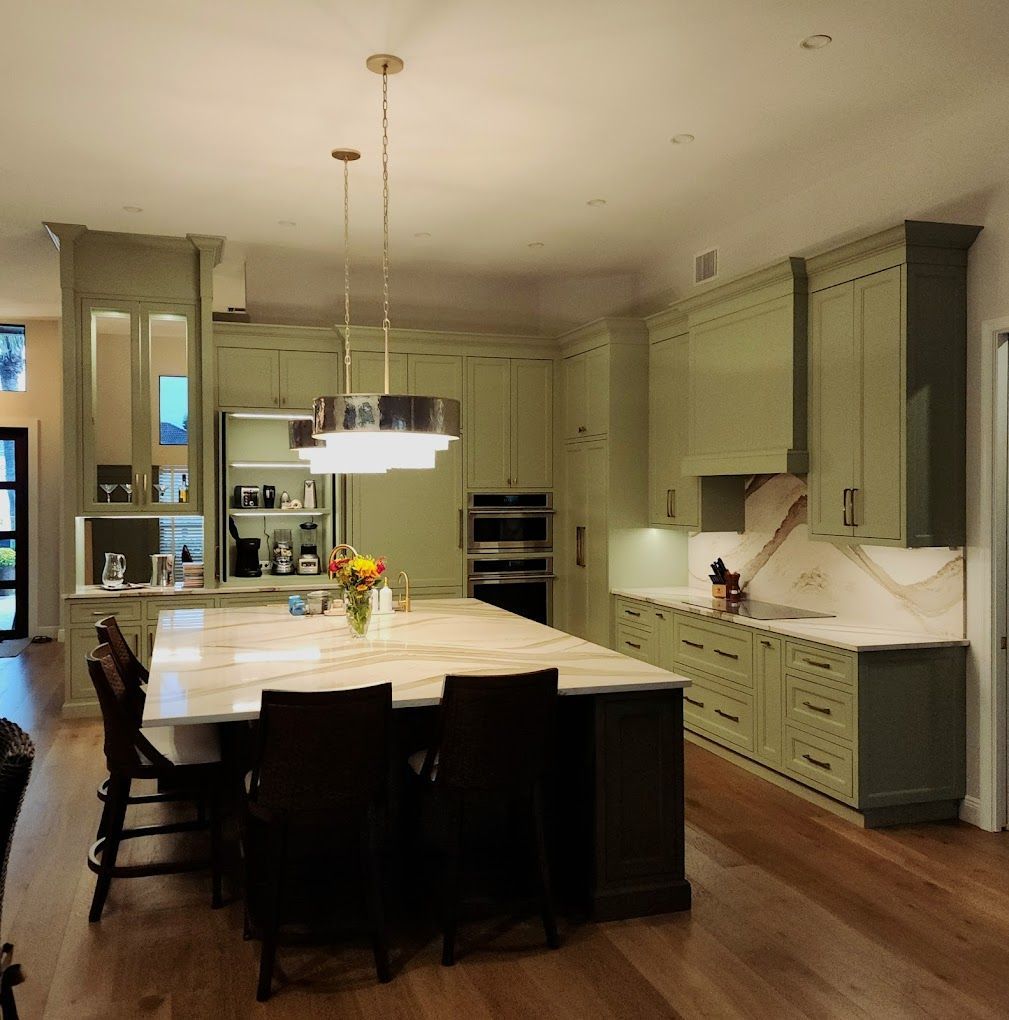 A kitchen with green cabinets and marble counter tops