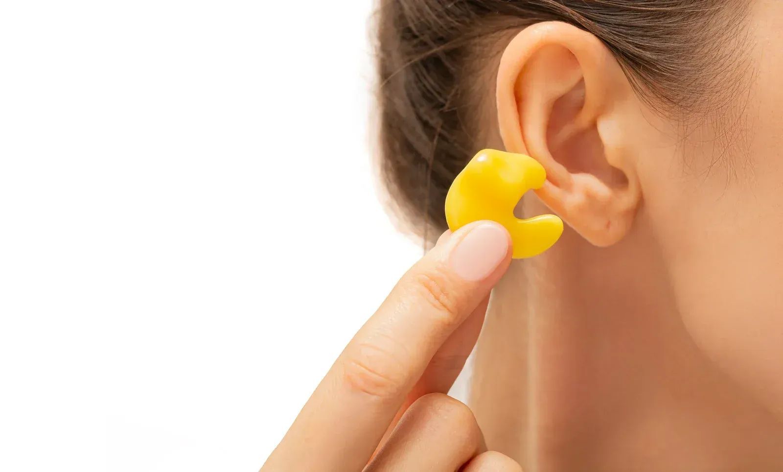 Person holding yellow earplug near ear, ready to insert it.