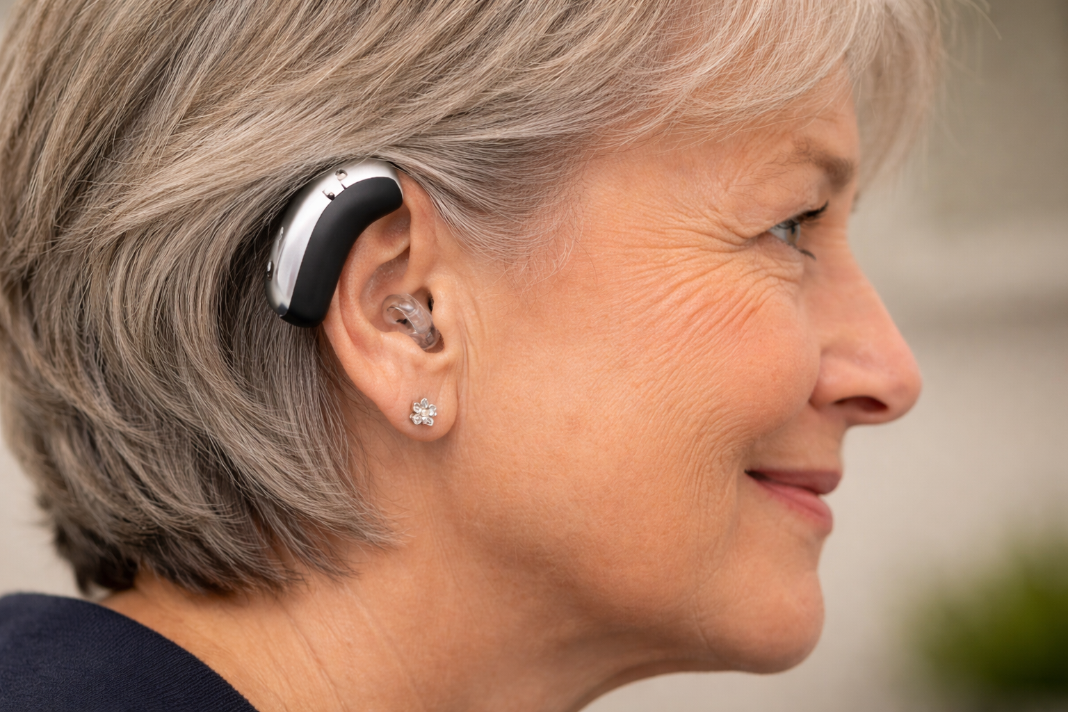 A person is holding a hearing aid in front of a man 's ear.