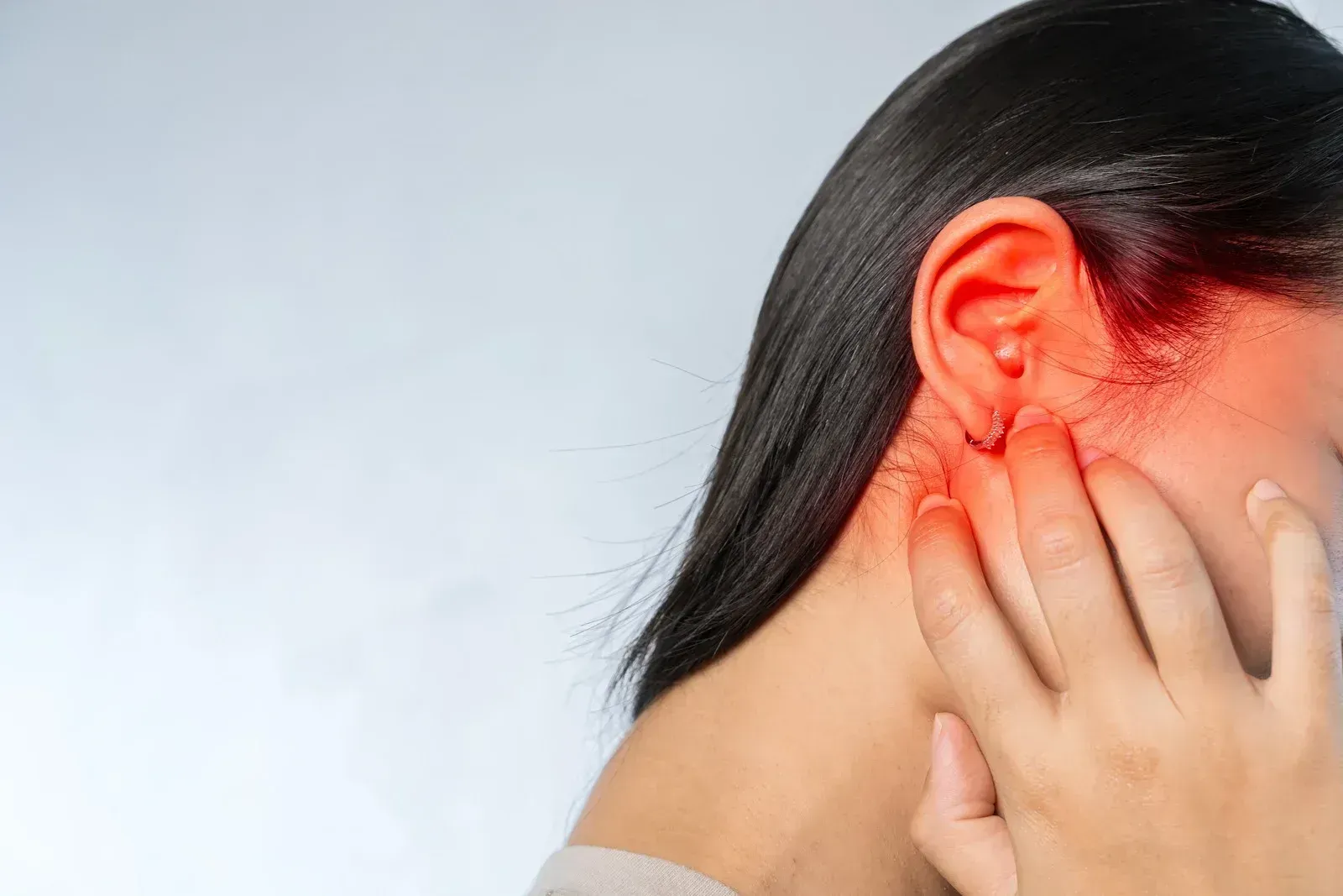 A woman is holding her ear in pain.