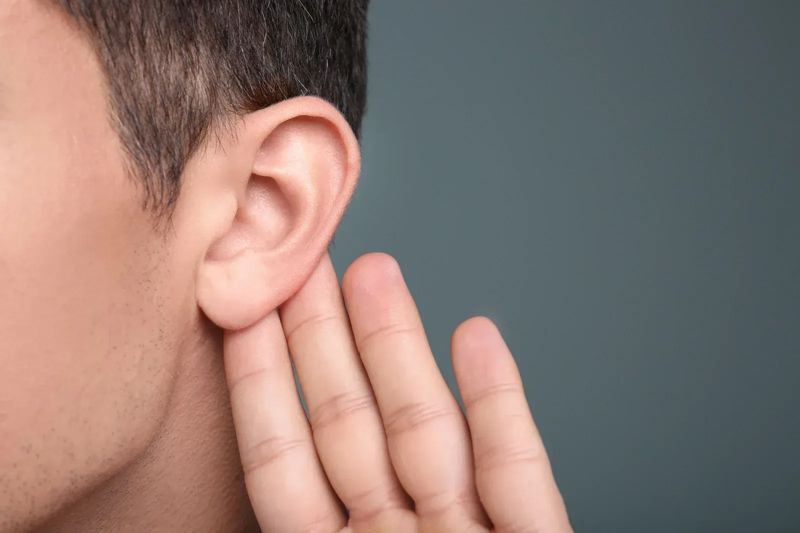 A man is holding his hand to his ear.