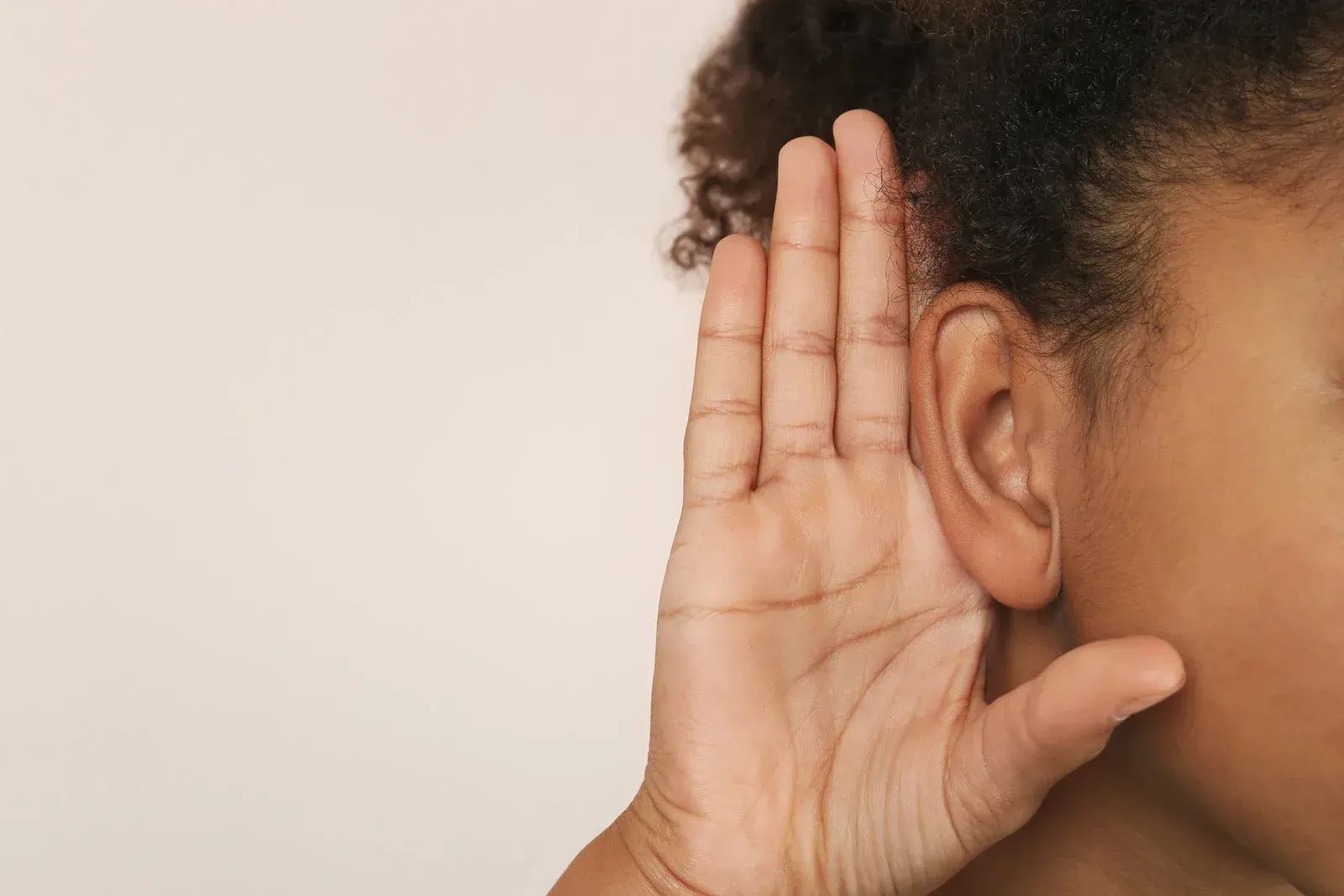 A woman is covering her ear with her hand.