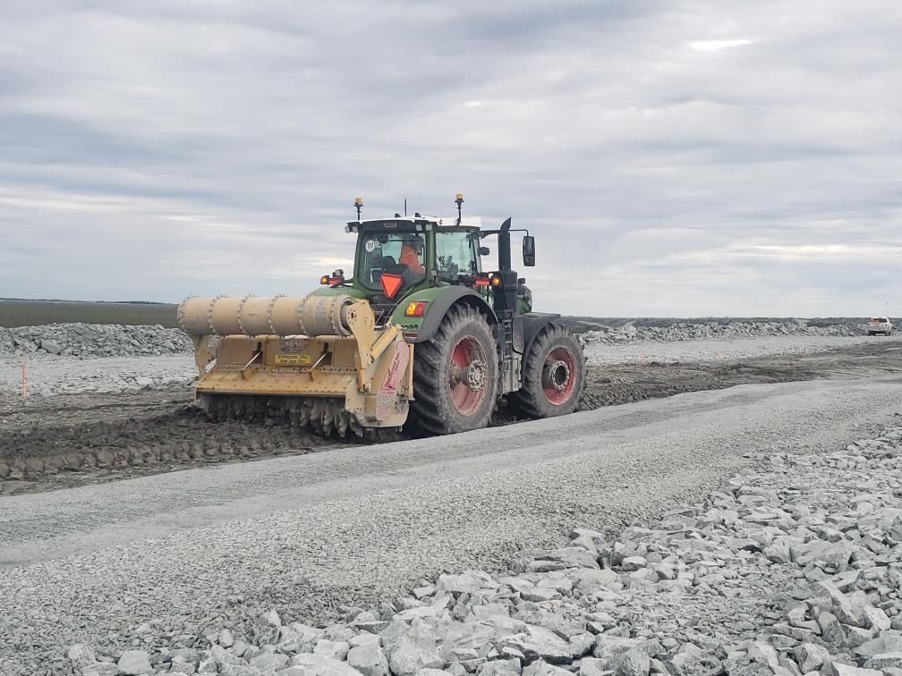 A tractor is driving down a gravel road.