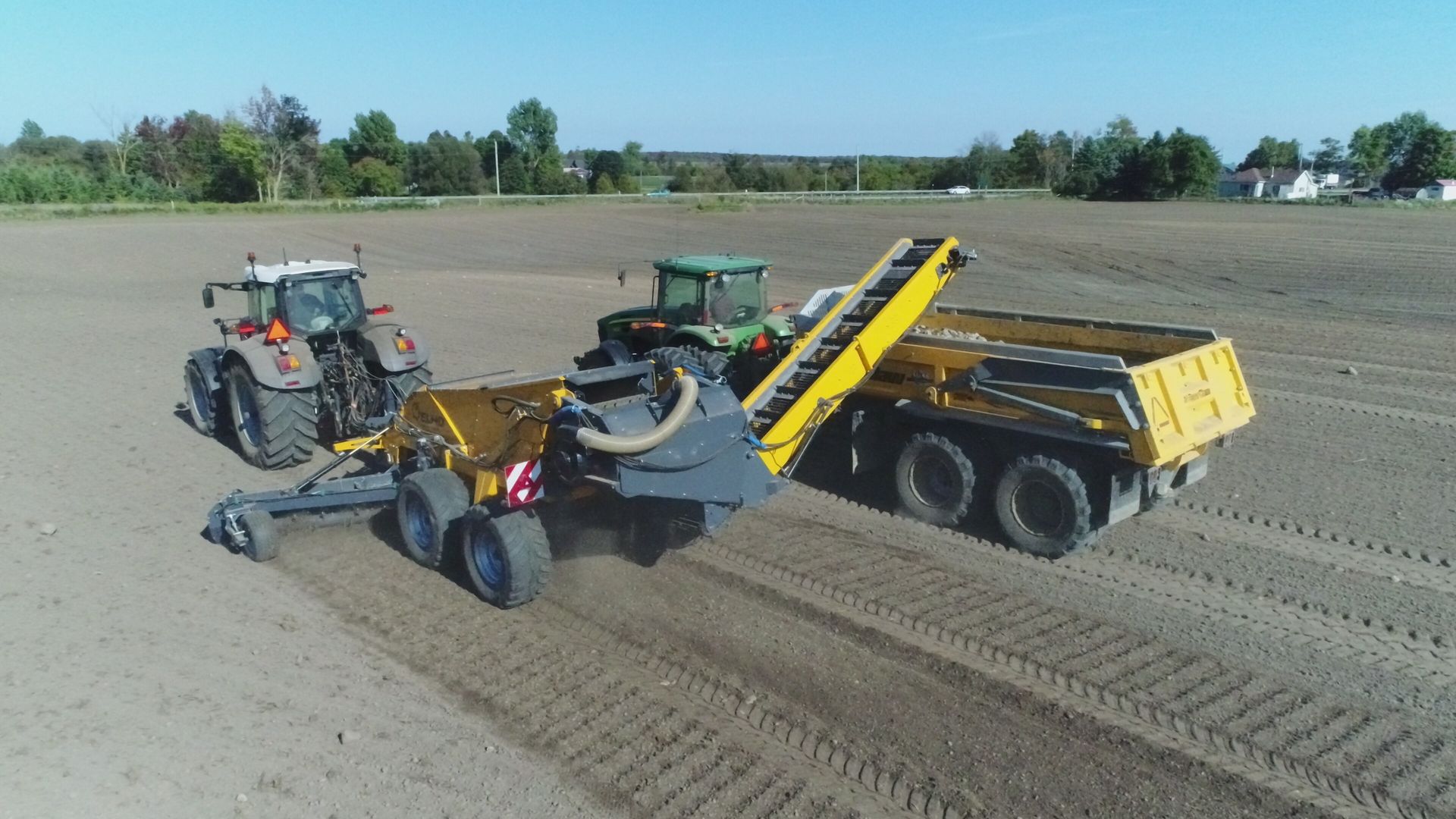 An aerial view of a tractor pulling a trailer in a field.