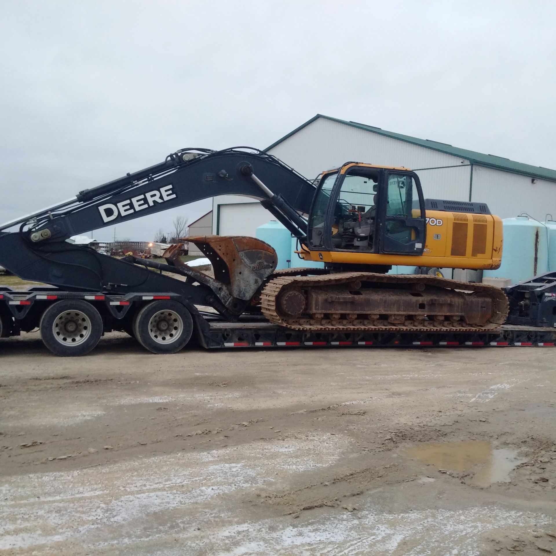 A deere excavator is being transported on a trailer