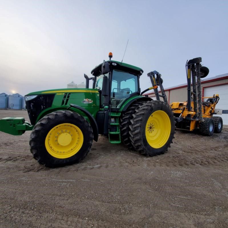 A green and yellow tractor is parked next to a yellow forklift