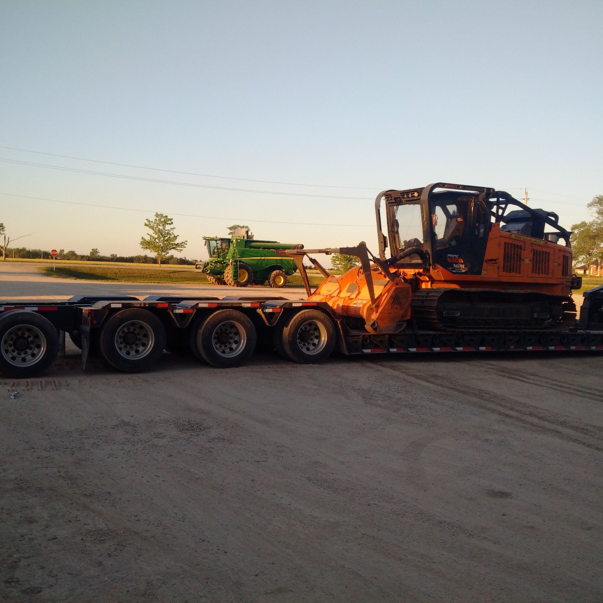 A bulldozer on a trailer with a green tractor in the background