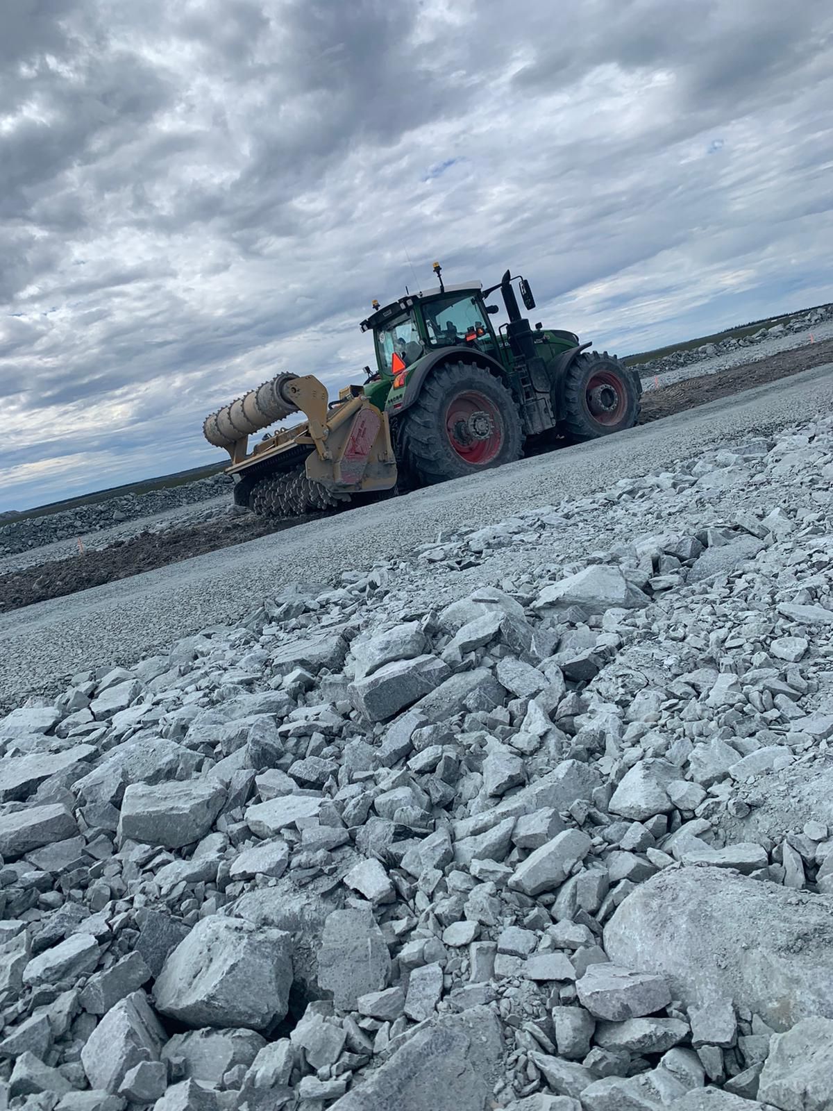 A tractor is driving down a rocky road.