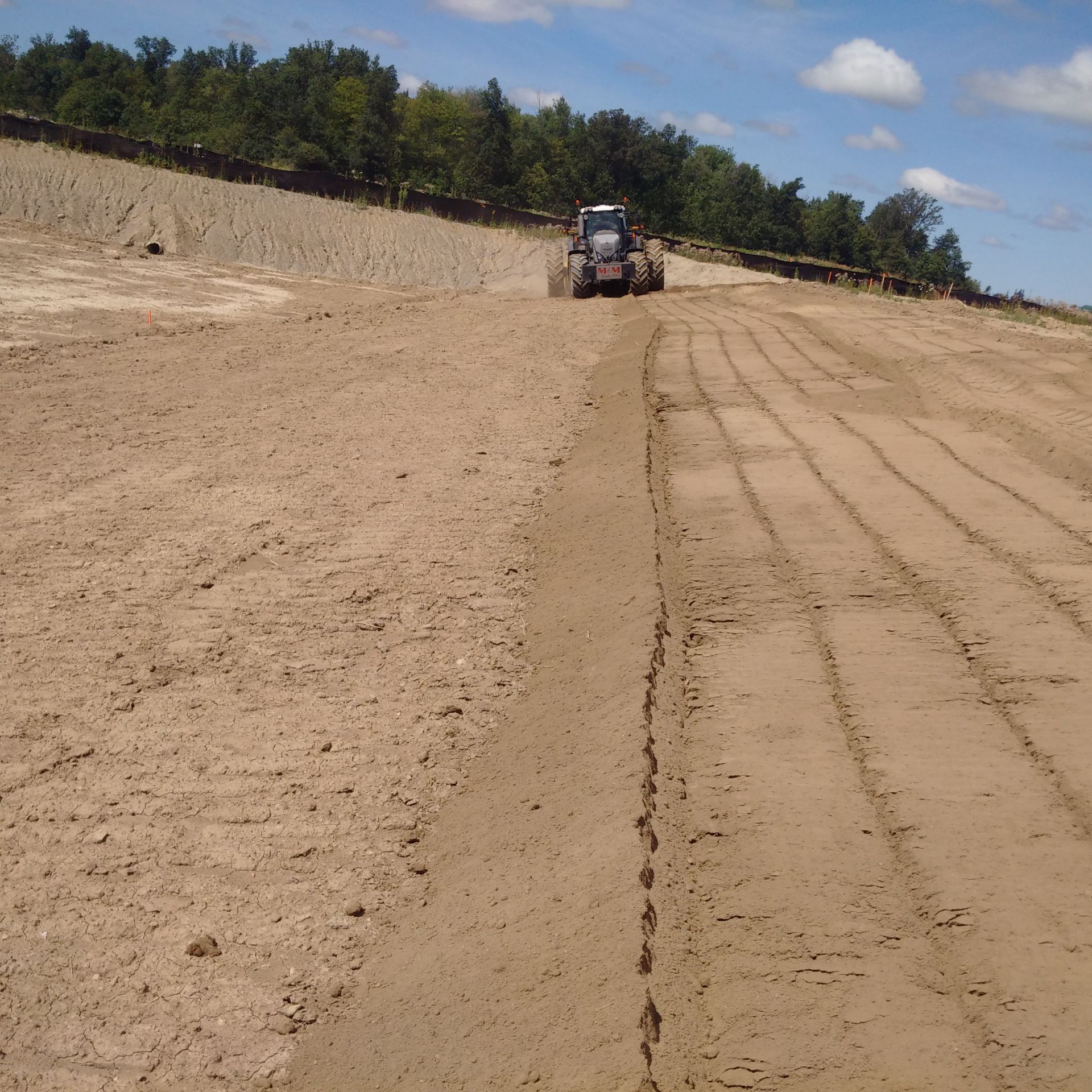 A tractor is driving down a dirt road