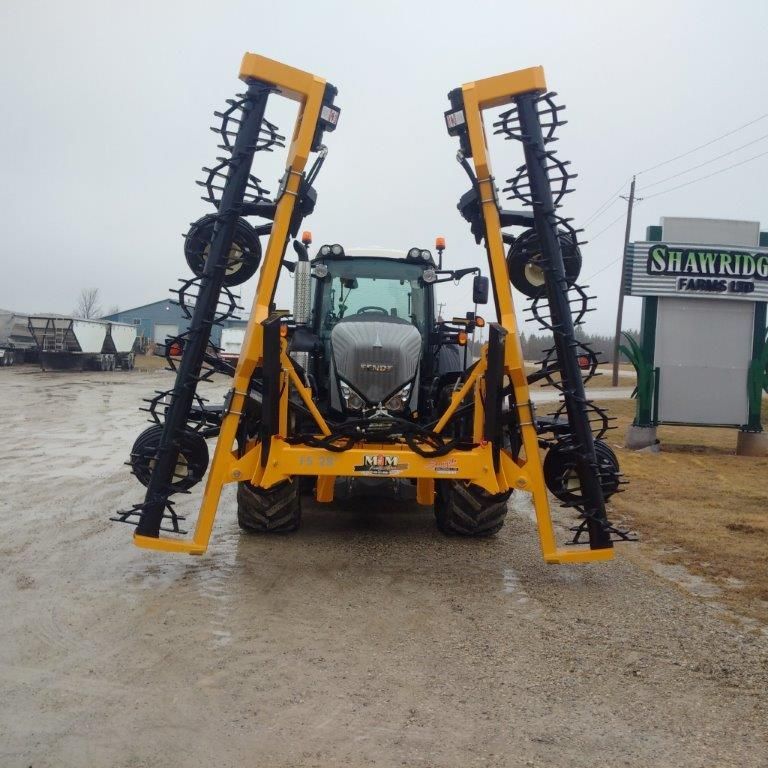 A yellow and black tractor is parked in front of a shawridge sign