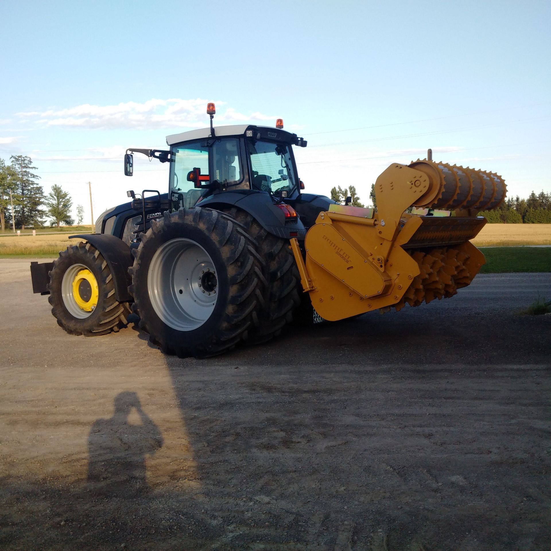 A black and yellow tractor is parked on a dirt road