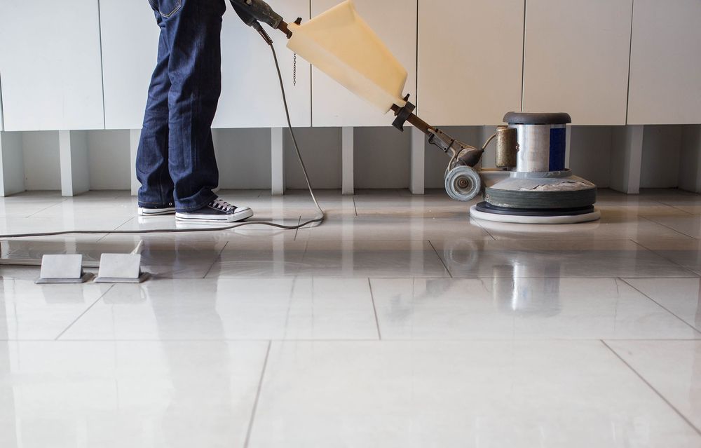 A person is cleaning a tiled floor with a machine.