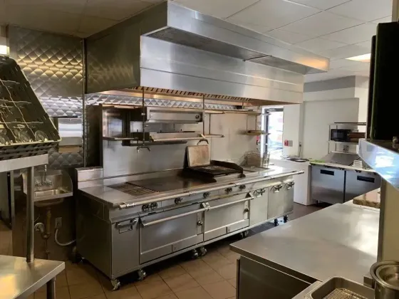 A large commercial kitchen with a lot of stainless steel appliances.