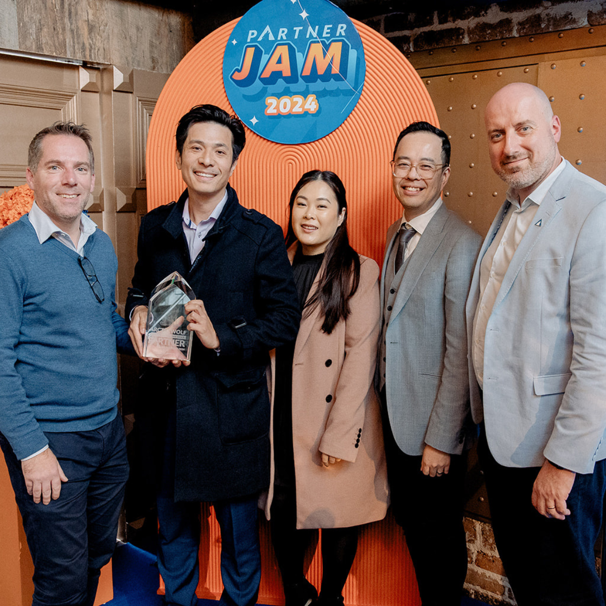 Five people pose with an award in front of an event backdrop labeled "Partner Jam 2024".