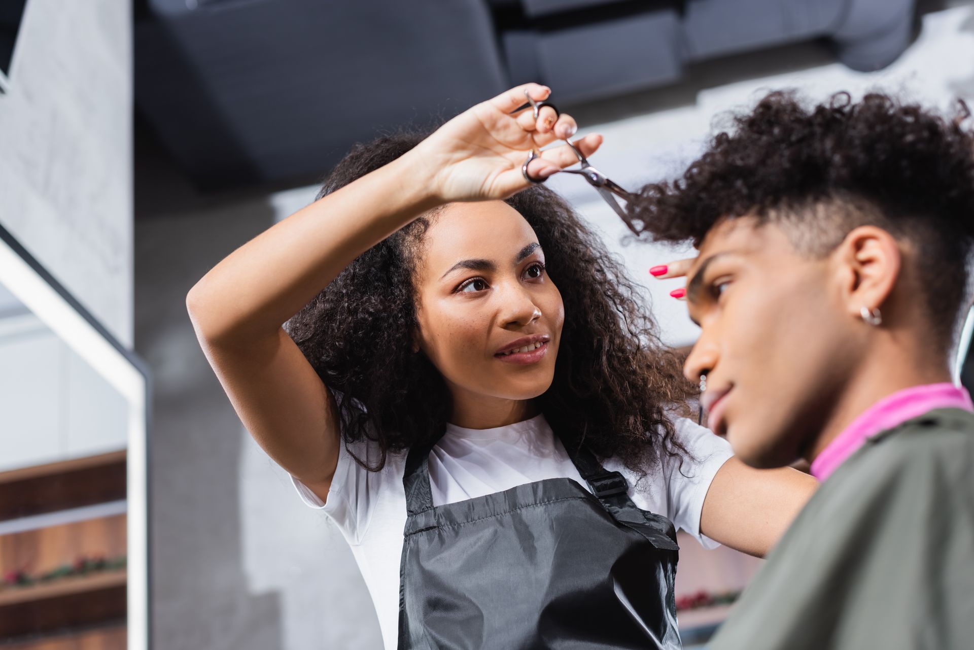 A woman is cutting a man 's hair in a salon.