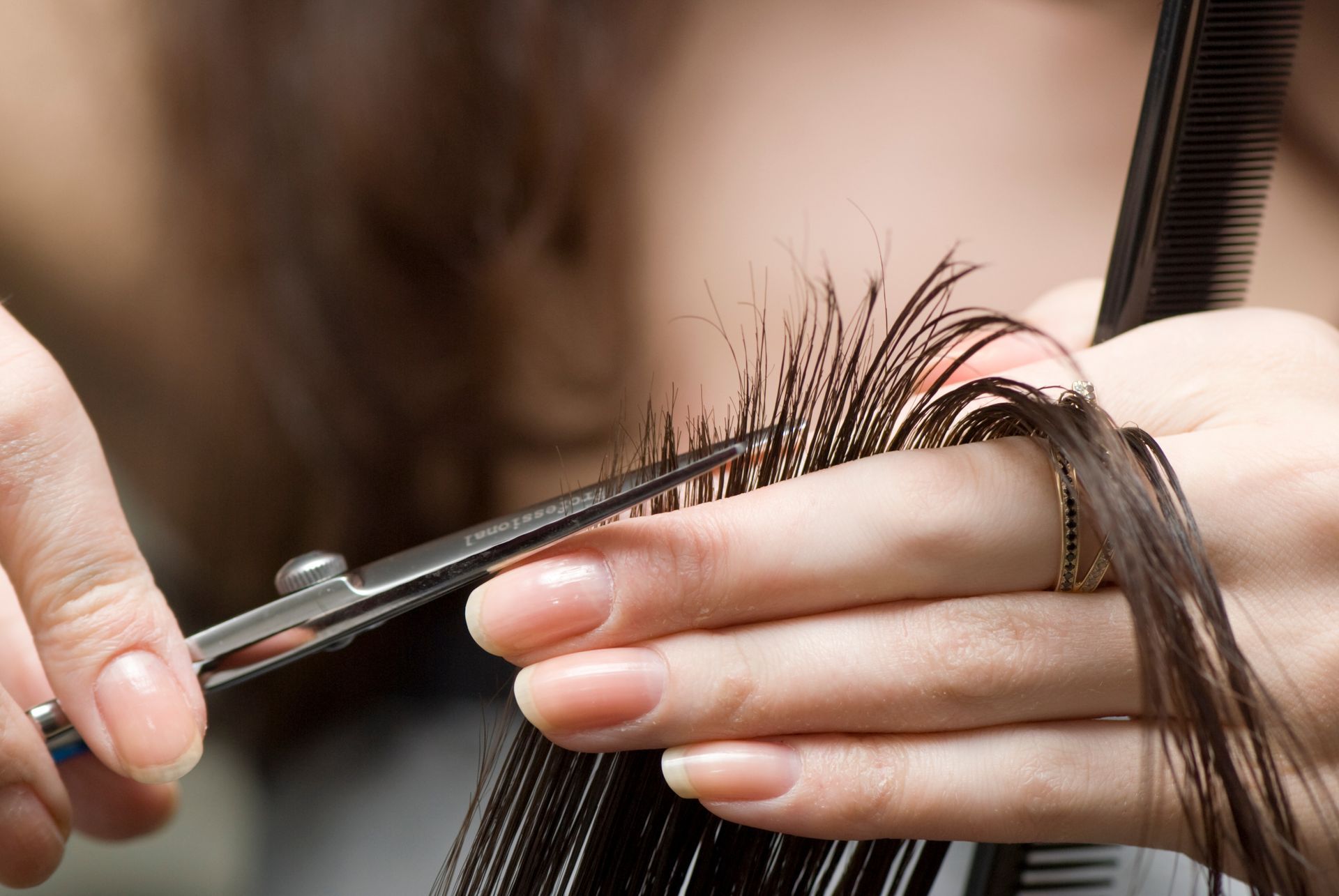 A woman is getting her hair cut by a hairdresser with scissors.