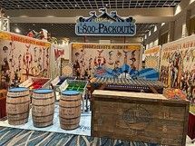 Disney-themed 1-800-Packouts booth with circus-style decor, barrels, and a treasure chest