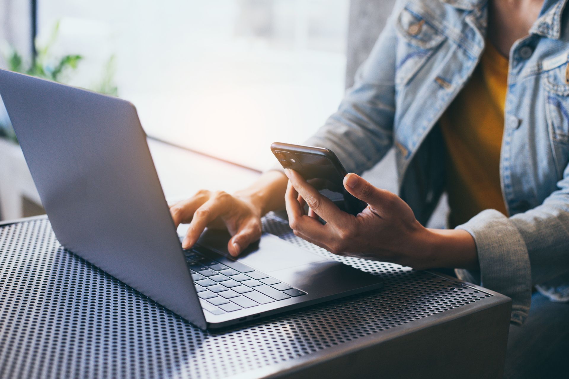 Person uses laptop and smartphone at a table