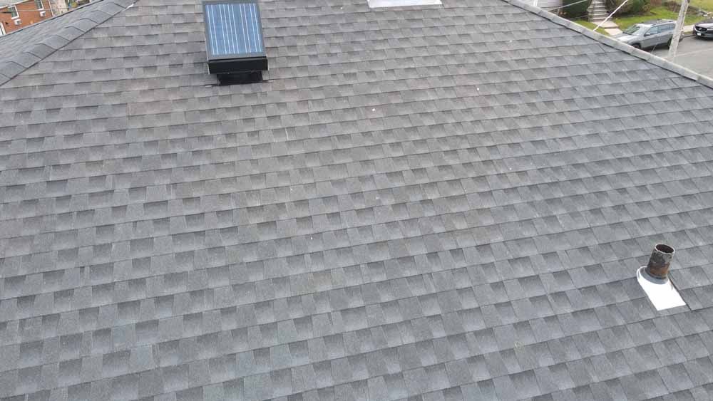 A roof with a skylight and a chimney on it.