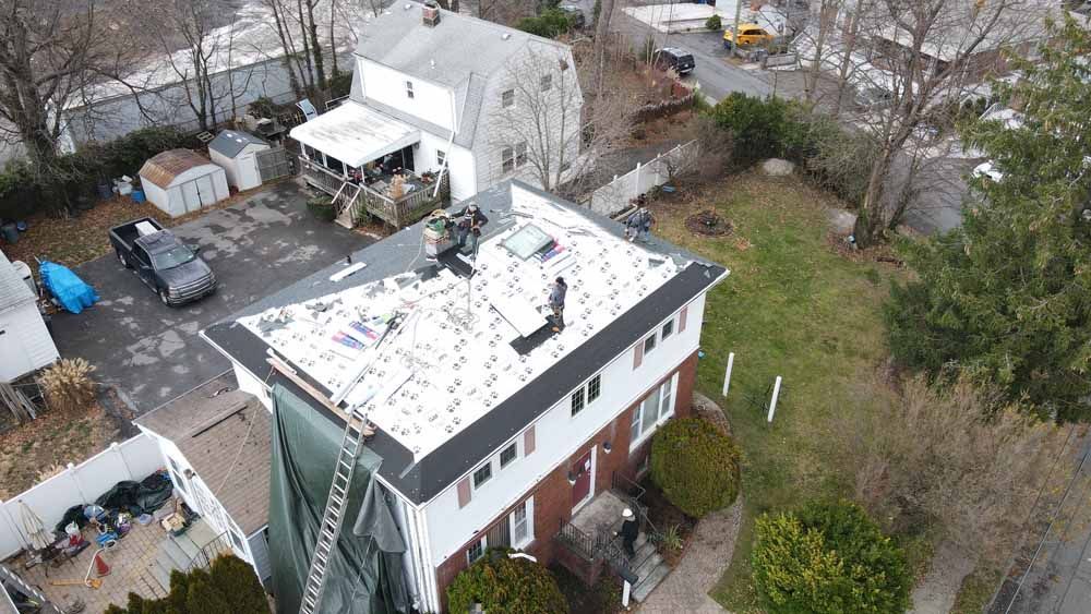 An aerial view of a house with a new roof being installed.