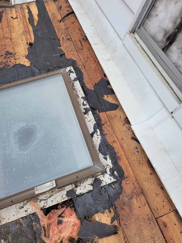 A skylight is sitting on top of a wooden floor next to a window.