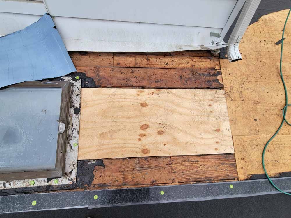 A piece of wood is laying on the ground next to a window.