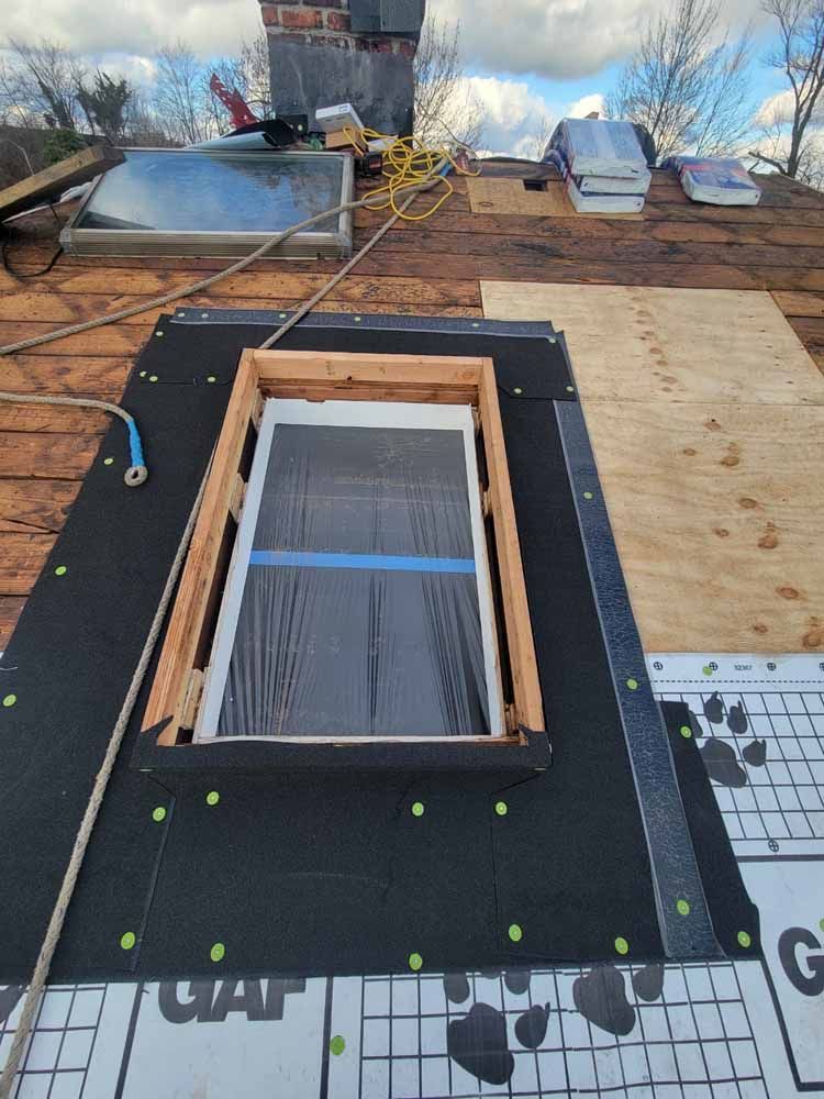 A window is being installed on the roof of a house.