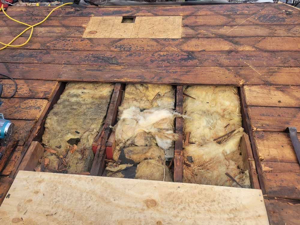 A wooden floor with a hole in it and a few pieces of insulation on it.